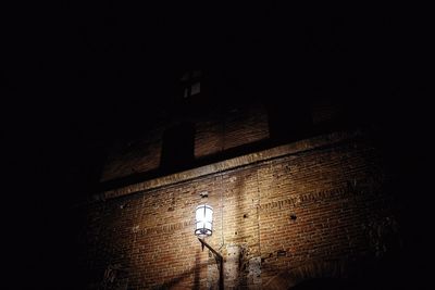 Low angle view of illuminated lamp on wall