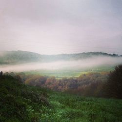 Scenic view of grassy field against cloudy sky