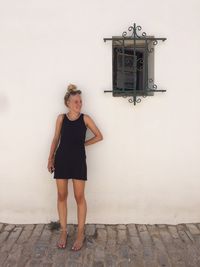 Happy woman standing against white building