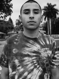 Portrait of young man standing against trees