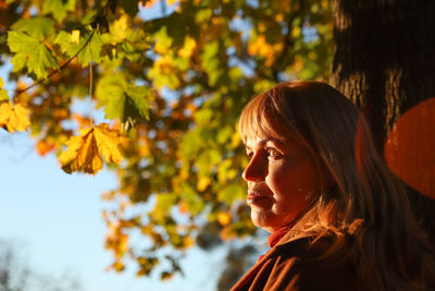 Portrait of beautiful caucasian blonde woman in colorful yellow maple autumn park. bright stylish 