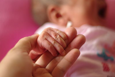 Cropped woman holding baby girl hand