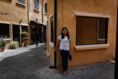 Portrait of woman standing against building in city