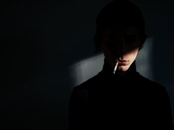 Close-up of man smoking cigarette in darkroom