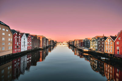 Canal amidst houses against sky during sunset