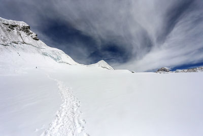 Scenic view of snow covered mountains against cloudy sky