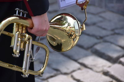 Midsection of man holding trumpet while standing on footpath