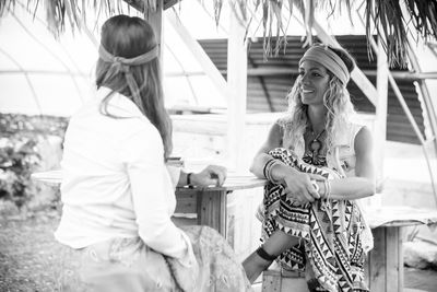 Smiling friends talking while sitting at outdoor cafe