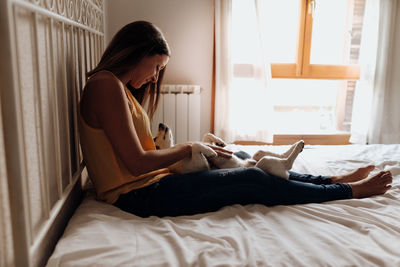 Side view of young woman using mobile phone in bed