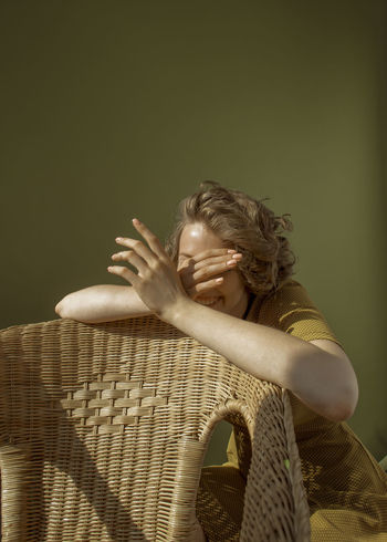 PORTRAIT OF GIRL WEARING HAT SITTING AGAINST WALL