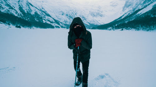 Full length portrait of man standing on snow covered land against mountains
