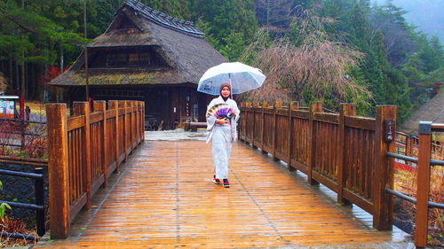 Full length of woman walking on road during rainy season