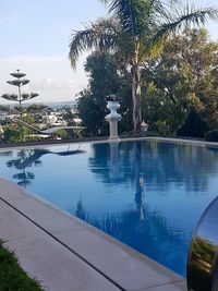 Swimming pool by trees against sky