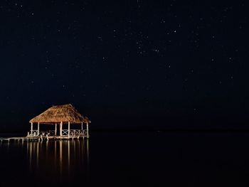 House on lake against sky at night