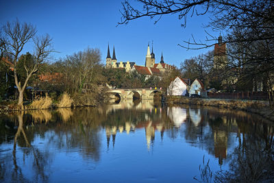 Reflection of trees and buildings in lake against sky