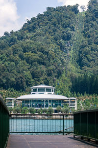 Built structure by trees and plants against sky