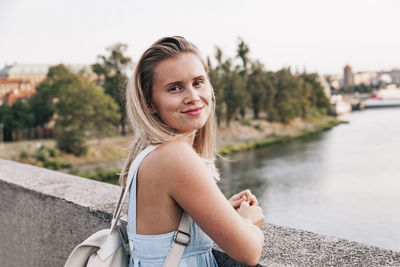 Portrait of smiling young woman against river