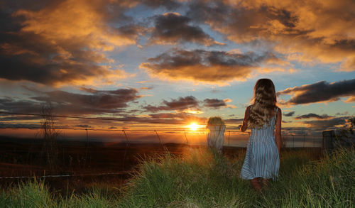 Rear view of girl on landscape at sunset