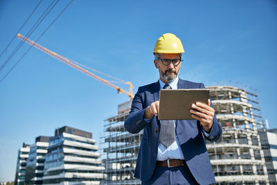 Low angle view of man holding umbrella at construction site