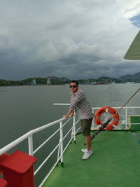 Full length of man standing on railing against sea