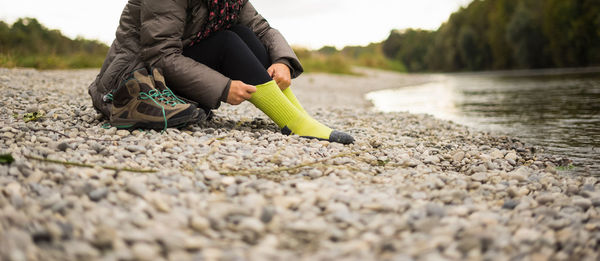 Low section of woman wearing sock on lakeshore