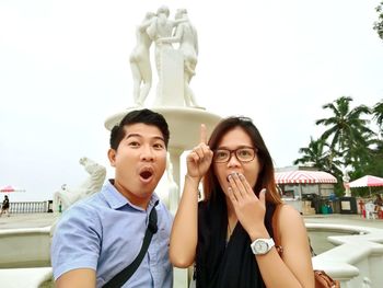 Portrait of couple standing against statue