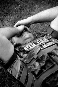 High angle view of sad police officer lying on field