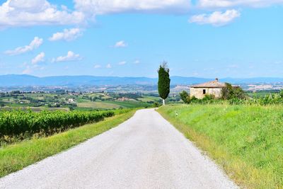 Road amidst field against sky