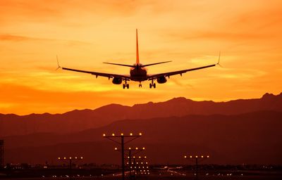 Low angle view of silhouette airplane flying against sky during sunset