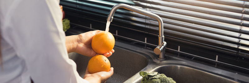 Cropped image of man holding orange fruit