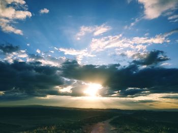 Sunlight streaming through clouds over landscape