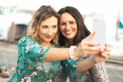 Smiling women taking selfie while standing outdoors