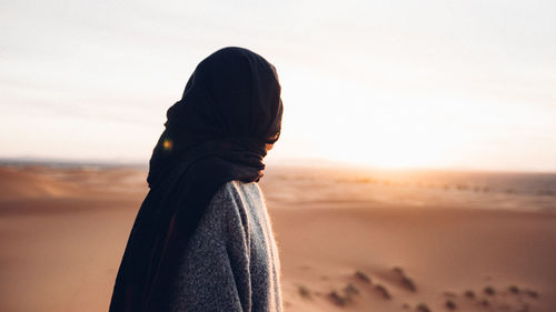 Woman standing on beach against sky during sunset