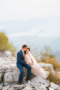 Full length of couple sitting on rock