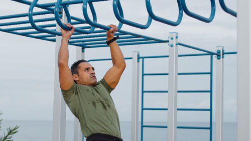 Man doing pull ups across monkey bar