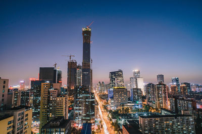 Illuminated buildings in city against clear sky at night