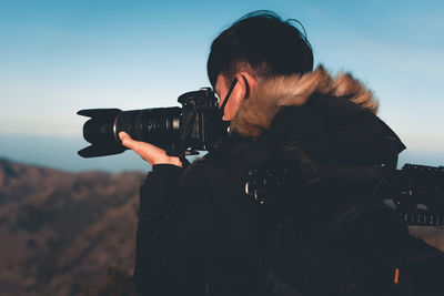 Man photographing with camera against sky