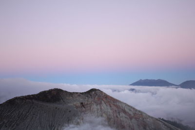 Scenic view of mountains against cloudy sky during sunset