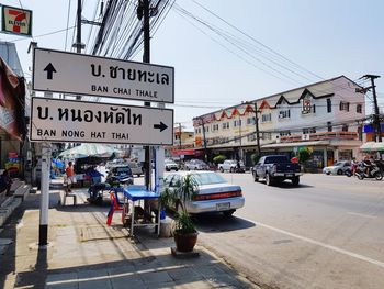 Information sign on street in city against sky