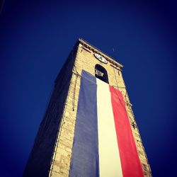 Low angle view of flag against clear blue sky