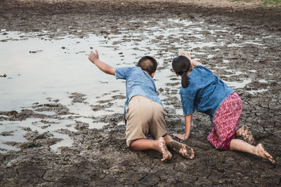 Siblings playing at muddy lakeshore