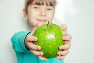 Portrait of boy holding apple against white background