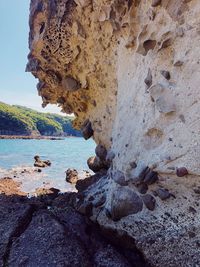 Rock formation on sea shore against sky