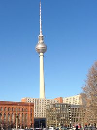 Communications tower in city against clear blue sky