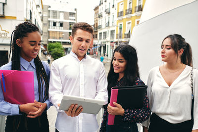 Friends standing by people in city