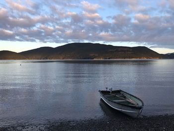 Boat moored on lake against sky