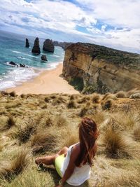 High angle view of woman sitting on mountain by beach