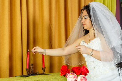 Young woman looking away while standing against curtain