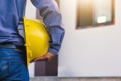 Midsection of man working with yellow umbrella