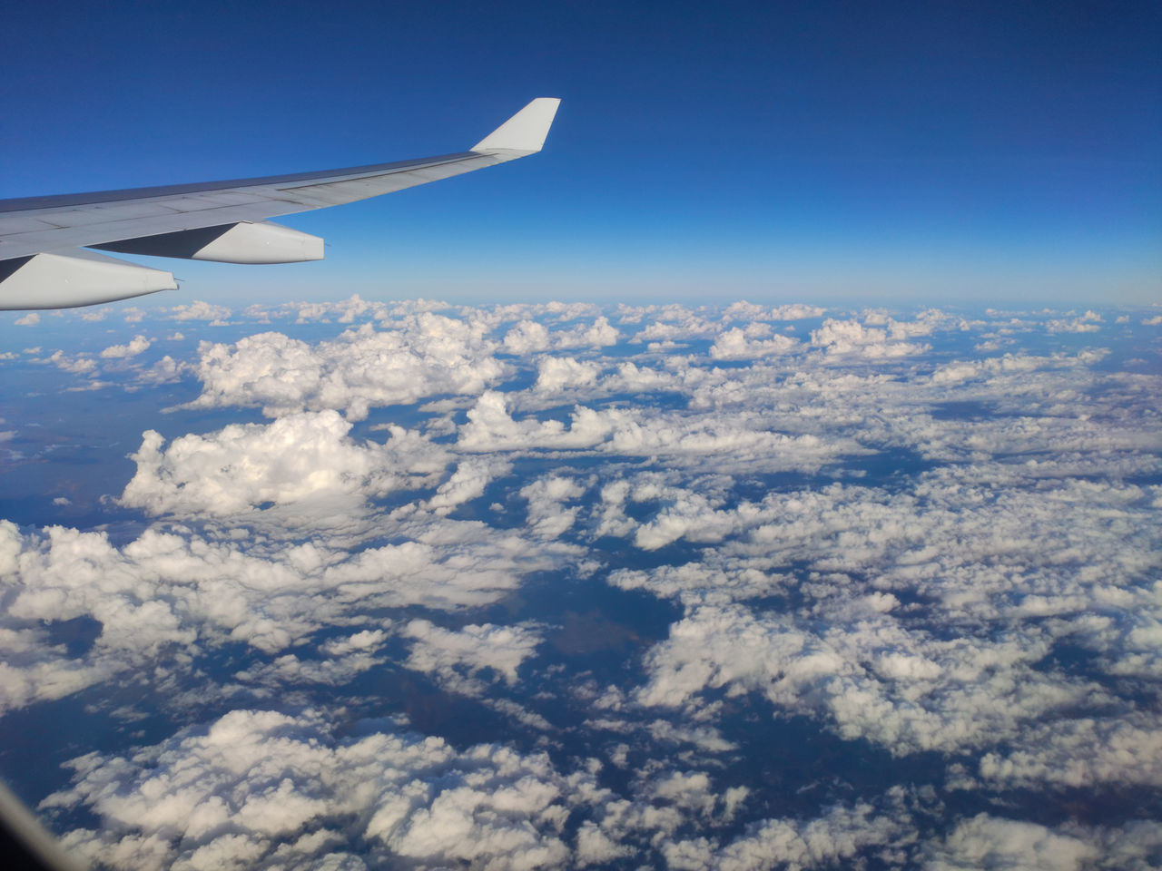 airplane, air vehicle, flying, aircraft wing, aerial view, transportation, sky, mode of transportation, travel, blue, cloud, nature, air travel, vehicle, environment, mid-air, journey, aircraft, scenics - nature, no people, aviation, landscape, day, beauty in nature, on the move, cloudscape, aerial photography, window, outdoors, motion, horizon, wing, vehicle interior, high up, reflection, travel destinations, atmosphere, above, horizon over land, urban skyline